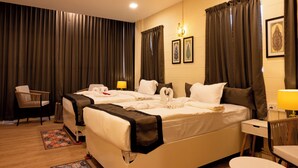 A hotel room with two beds, a desk, a chair, a lamp, and curtains.