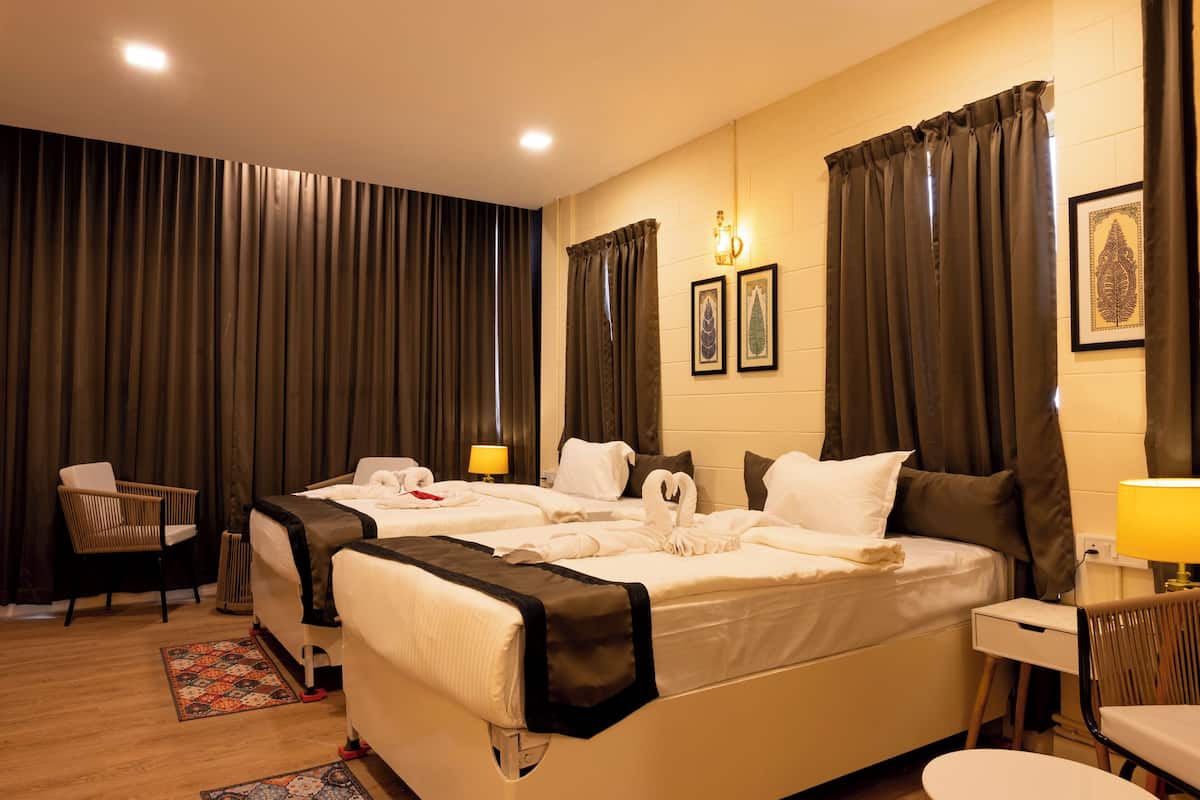 Une chambre d’hôtel avec deux lits, un bureau, une chaise, une lampe et des rideaux.
