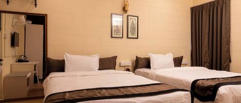 A hotel room with two beds, a desk, a mirror, and a shower curtain.