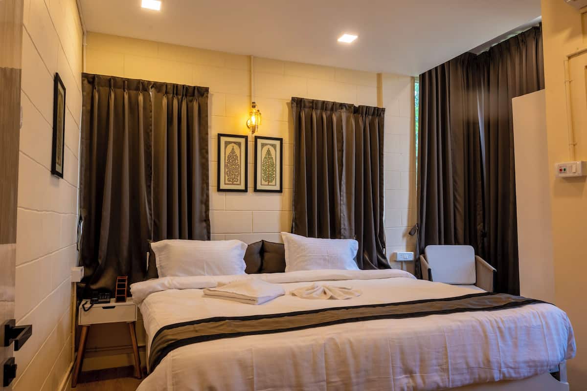 Une chambre d’hôtel avec un grand lit, une table de chevet, une chaise et deux appliques murales.