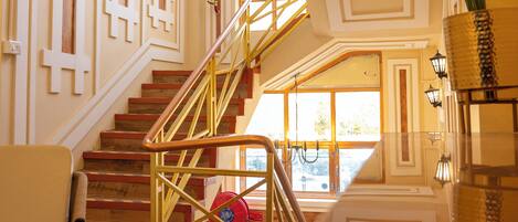 Un grand escalier, avec une borne d’incendie rouge, une plante en pot et une chaise.