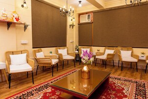 Una habitación con sillas de mimbre, una mesa de centro de vidrio y un tapete rojo estampado.