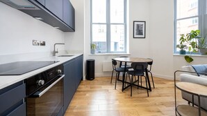 Eine kleine Küche mit dunklen Schränken, einem eingebauten Backofen und einem Fenster, das für natürliches Licht sorgt.