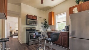 A modern kitchen with stainless steel appliances, wooden cabinets, and a bar area with stools. - Comfy One Bed Apartment in Forest Park (Forest Park)