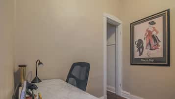 Un pequeño espacio de oficina con un escritorio, una silla, una lámpara y un cuadro en la pared.