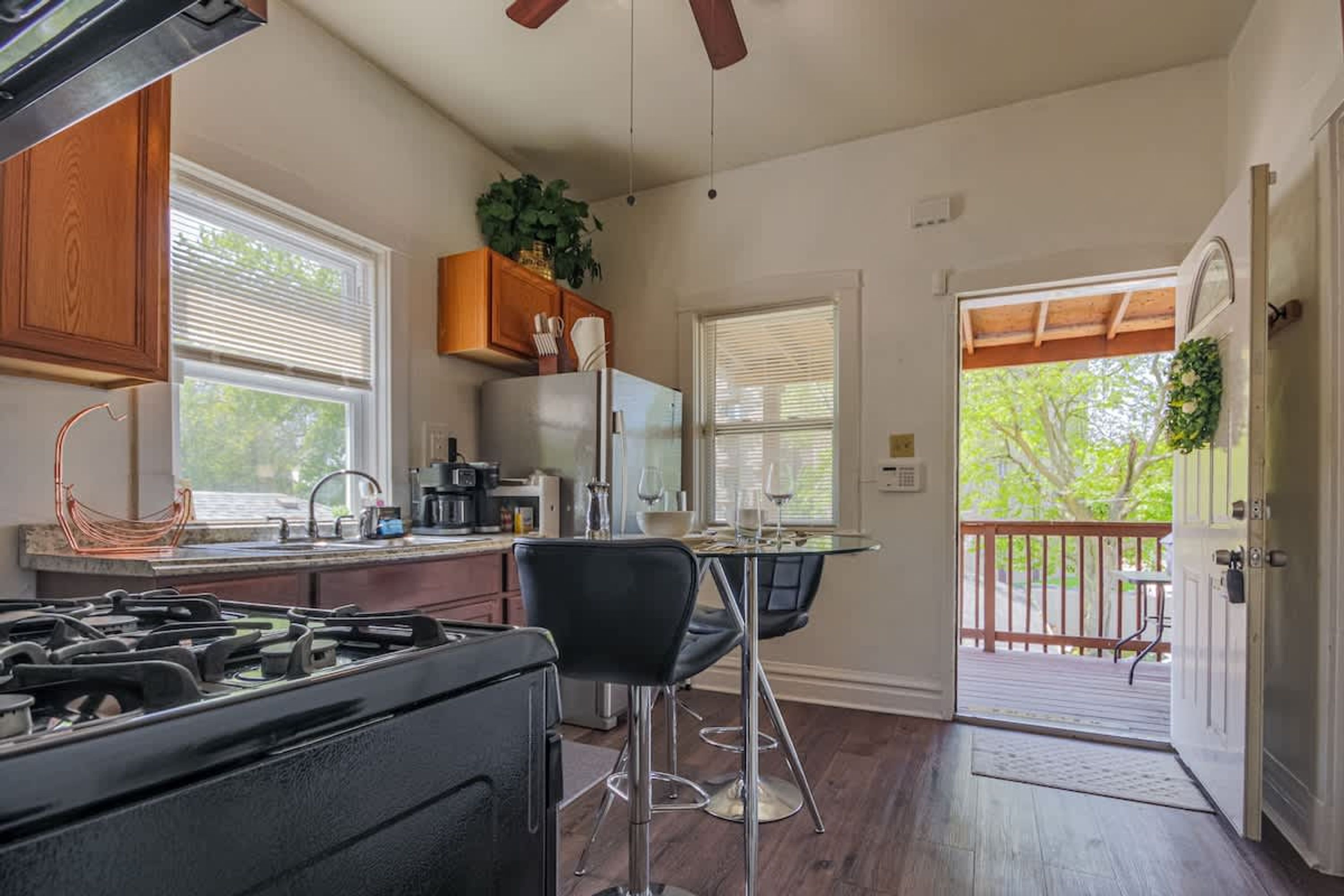 A kitchen with a gas stove, wooden cabinets, a refrigerator, and a dining area with a table and chairs.