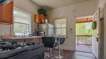 A kitchen with a gas stove, wooden cabinets, a refrigerator, and a dining area with a table and chairs.