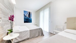 A modern hotel room with a large bed, a small table with a potted plant, a chair, and a painting on the wall. - Two-room Apartment Scola 12 (Gabicce Mare)