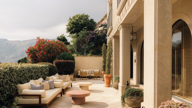 Un patio exterior con sofá, mesa redonda y plantas en macetas.