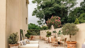 Un patio exterior con piscina, sillones de descanso y zona de comedor.
