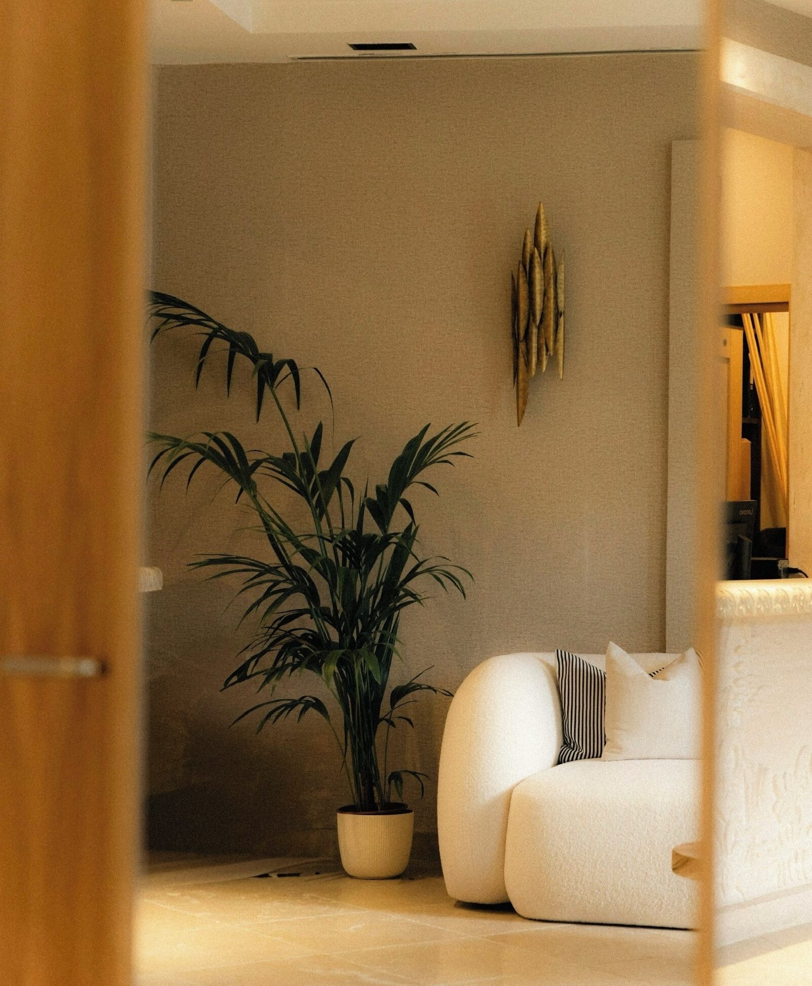 Un salon moderne avec un canapé blanc, une plante en pot et un élément décoratif mural.