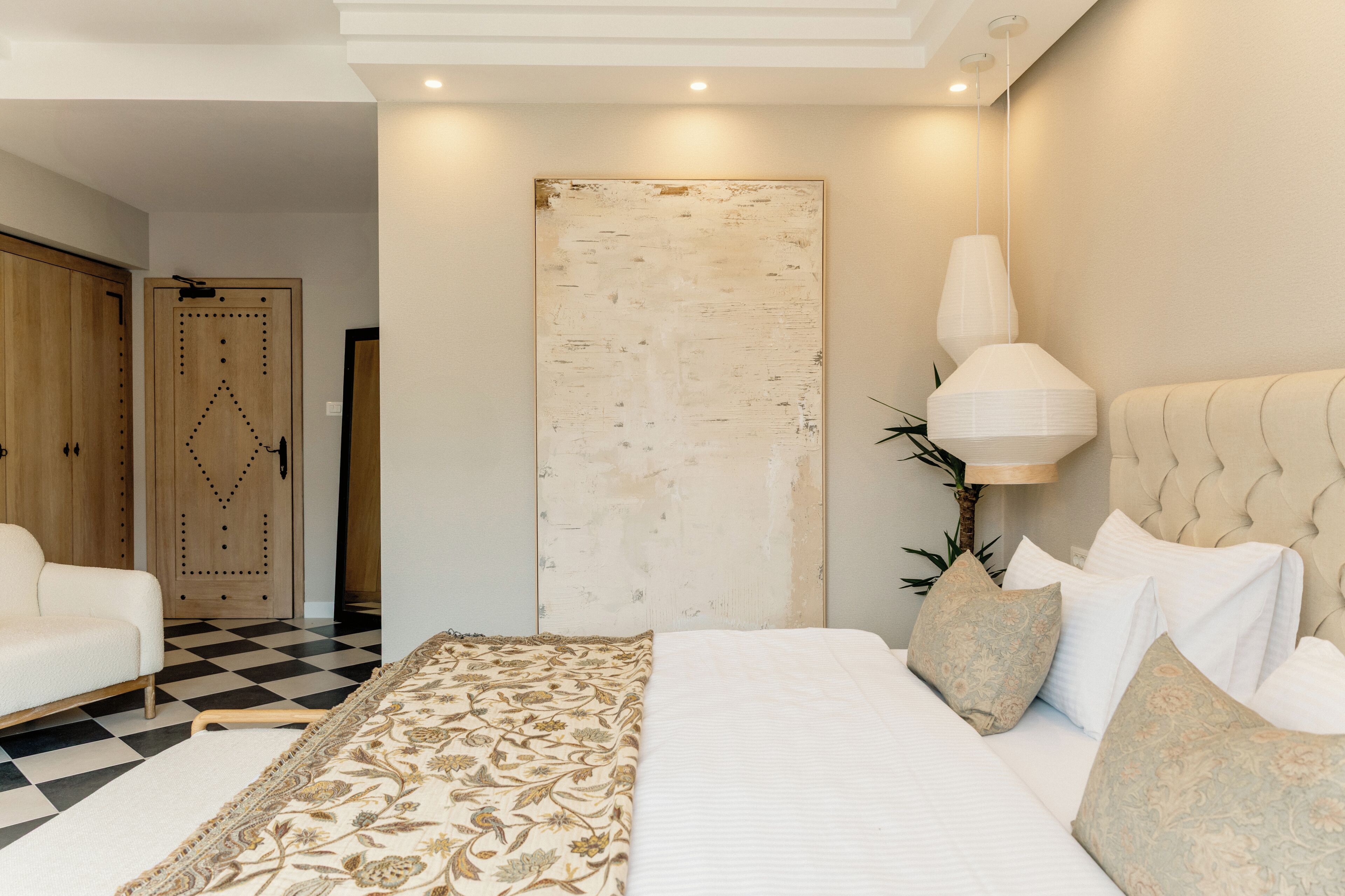 Un dormitorio con una cama grande, piso a cuadros, un armario de madera y una obra de arte colgada en la pared.