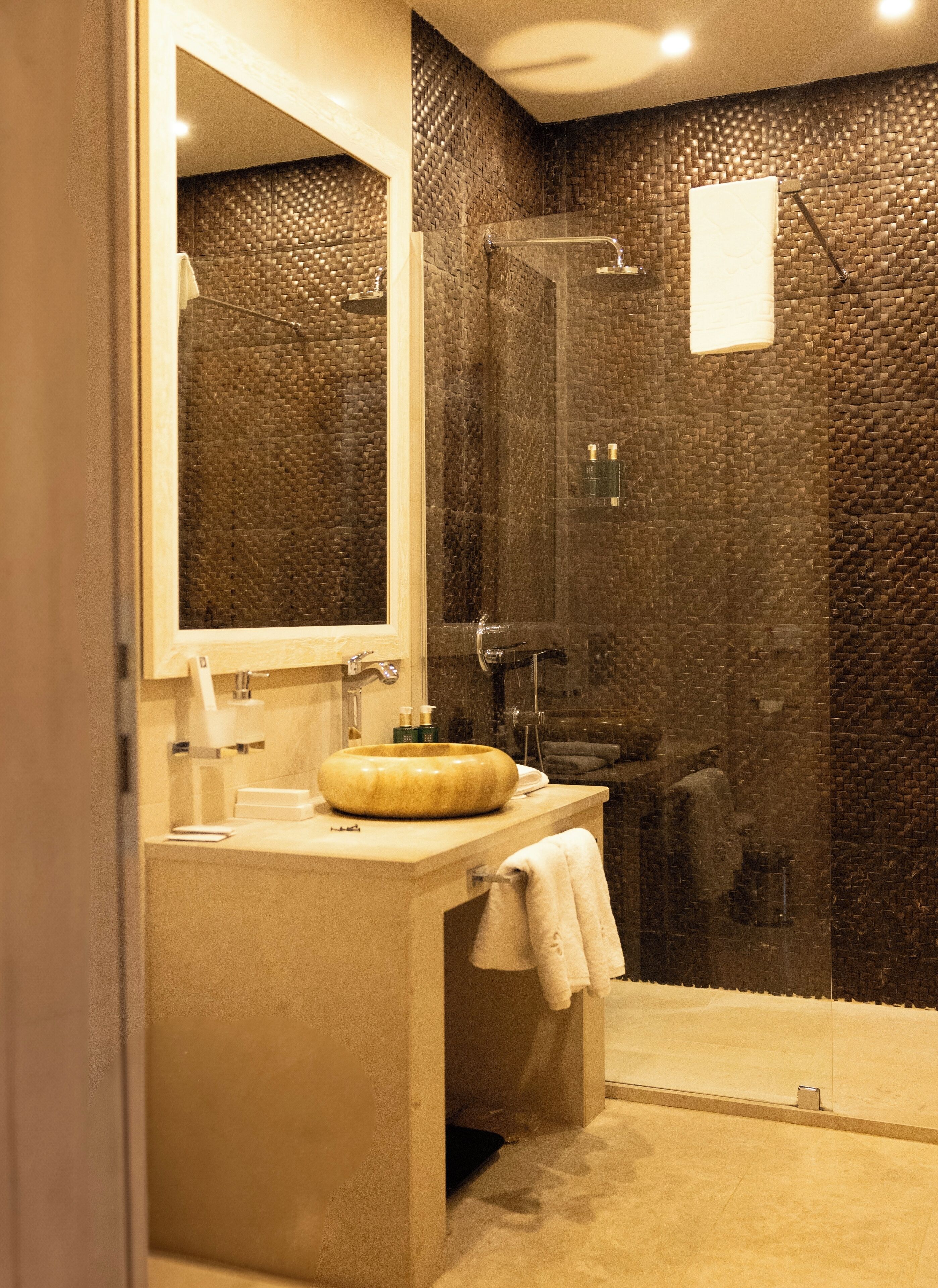 A modern bathroom with a round sink, a glass shower enclosure, and a large mirror.