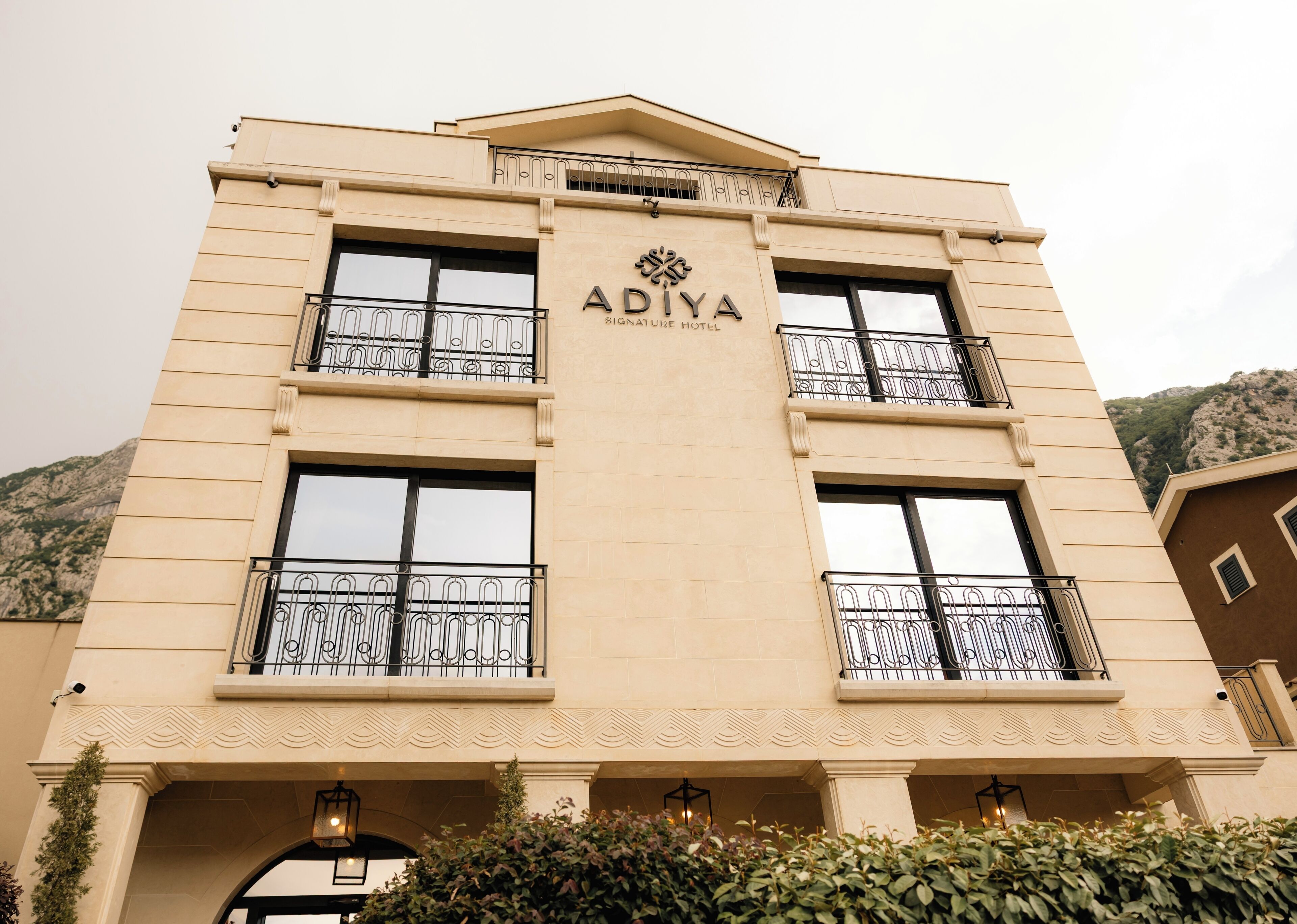 Um edifício de hotel com o nome 'ADIVA' na fachada, apresentando um design simétrico com varandas e uma entrada central.