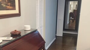 A hallway with a wooden floor, a piano, a framed painting, and a closed door. - Stylish In-law Suite in Frederick (Frederick)