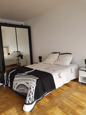 A bedroom with a bed, bedside tables, a mirror, and a wardrobe.