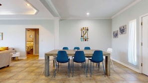A dining area with a wooden table and blue chairs, a living room with a sofa and a small table, and a hallway with a door.