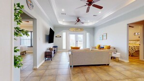 A spacious living room with a large sofa, a television, and a ceiling fan.