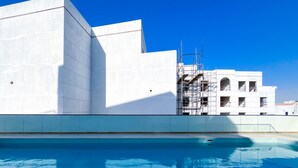 A modern building with a pool in front. - JVC Hideaway: Studio With Balcony and Amenities (Dubai)