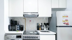A compact kitchen with a washing machine, microwave, stove, and oven. - JVC Hideaway: Studio With Balcony and Amenities (Dubai)