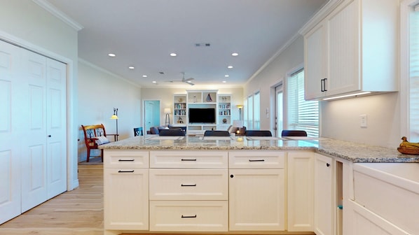 Una cocina moderna con armarios blancos, encimera de granito y una isla central.