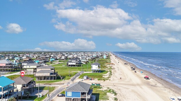 A coastal residential area with houses, a beach, and a clear sky. - At Tides Edge: 3  BR, 3  BA House in Crystal Beach, Sleeps 12 (Bolivar Peninsula)