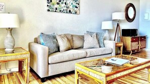 Ein Wohnzimmer mit einer Couch, einem Couchtisch, Lampen und einem Fernseher.