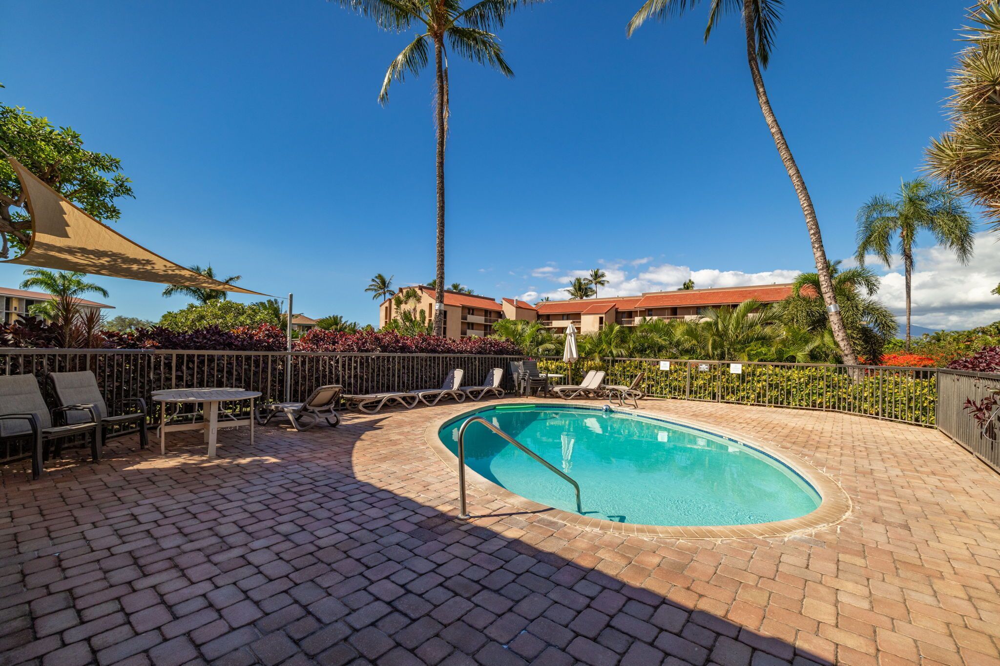 A swimming pool with lounge chairs and a brick patio.
