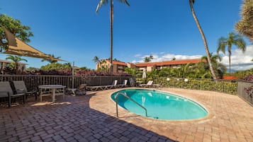 A swimming pool with lounge chairs and a brick patio.