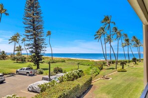 A beachfront property with a parking area, a covered carport, and a view of the ocean.