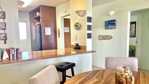 A modern kitchen with a wooden countertop, a dining table with chairs, and a decorative centerpiece.