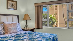 A hotel room with a bed, a nightstand, a lamp, a window with curtains, and a framed picture on the wall.