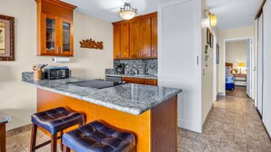 Una cocina con armarios de madera, encimera de mármol y una isla integrada con taburetes de bar.