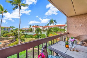 A balcony with a table, a bottle of champagne, and a chair. - Bright & Airy Remodeled Corner End Unit - Walking to Sandy Beaches! (Kihei)