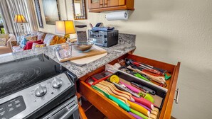 Una cocina con estufa, tostadora y un cajón con utensilios de colores.