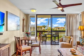 A hotel room with a balcony, a dining area, and a seating area with a view of the ocean and buildings. - FALL SPECIAL!!! Spacious & Remodeled Maui Vista 3213 Corner Unit! (Kihei)