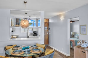 A modern kitchen with a dining area, a large window with a view, and a ceiling fan. - Stunning Premium Direct Ocean Front Escape! (Kihei)