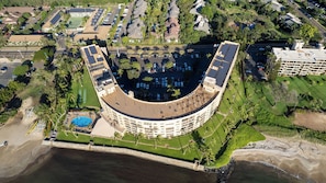 An aerial view of a resort with a curved building, a swimming pool, and a beach. - FALL SPECIAL!! PREMIUM OCEANFRONT UNIT WHER THE OCEAN MEETS THE SKY!!! (Kihei)