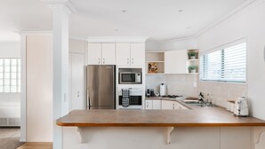 Een moderne keuken met witte kastjes, roestvrijstalen apparatuur en een houten aanrecht.