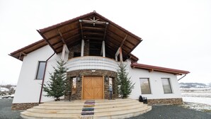 A two-story building with a wooden facade, a balcony with a white railing, and a wooden door. - Casa Danciu Fanate – Tradiție, liniște și ospitalitate în inima naturii (Cernești)