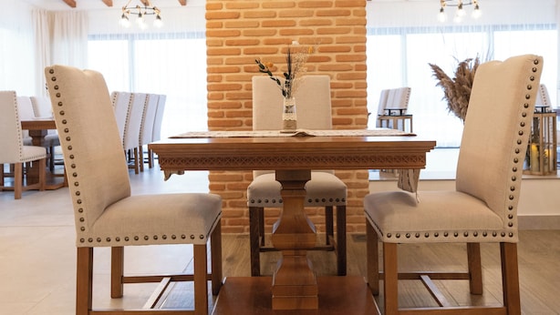 A dining area with a brick wall, wooden ceiling beams, and a wooden dining table with chairs. - Casa Danciu Fanate – Tradiție, liniște și ospitalitate în inima naturii (Cernești)