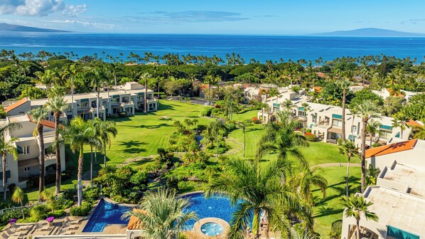 A resort with multiple buildings, a swimming pool, and a view of the ocean.