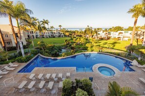 A resort with a swimming pool, lounge chairs, and a view of the ocean.