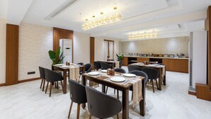 A modern dining area with multiple tables, chairs, and a kitchen in the background. - Treebo Premium Taara (Chennai)