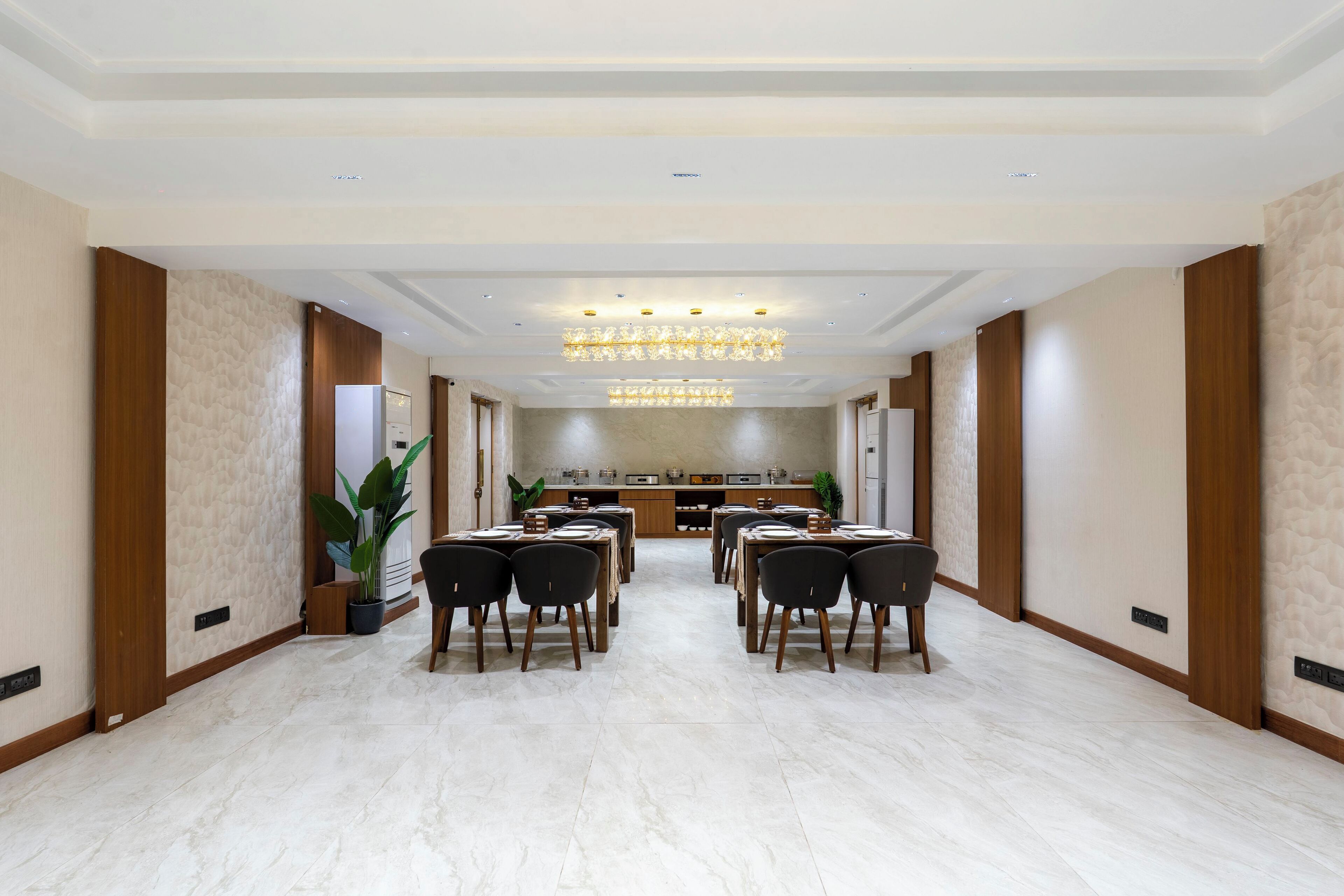 Ein geräumiger Speisesaal eines Hotels mit einem langen Tisch, der für mehrere Gäste gedeckt ist, einer Kandelaber und einer Küche im Hintergrund.