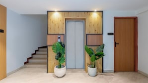 A modern interior with a wooden door, a staircase, and two potted plants. - Treebo Premium Taara (Chennai)