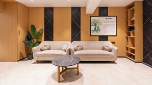 A modern reception area with a beige sofa, a round marble table, and a potted plant. - Treebo Premium Taara (Chennai)