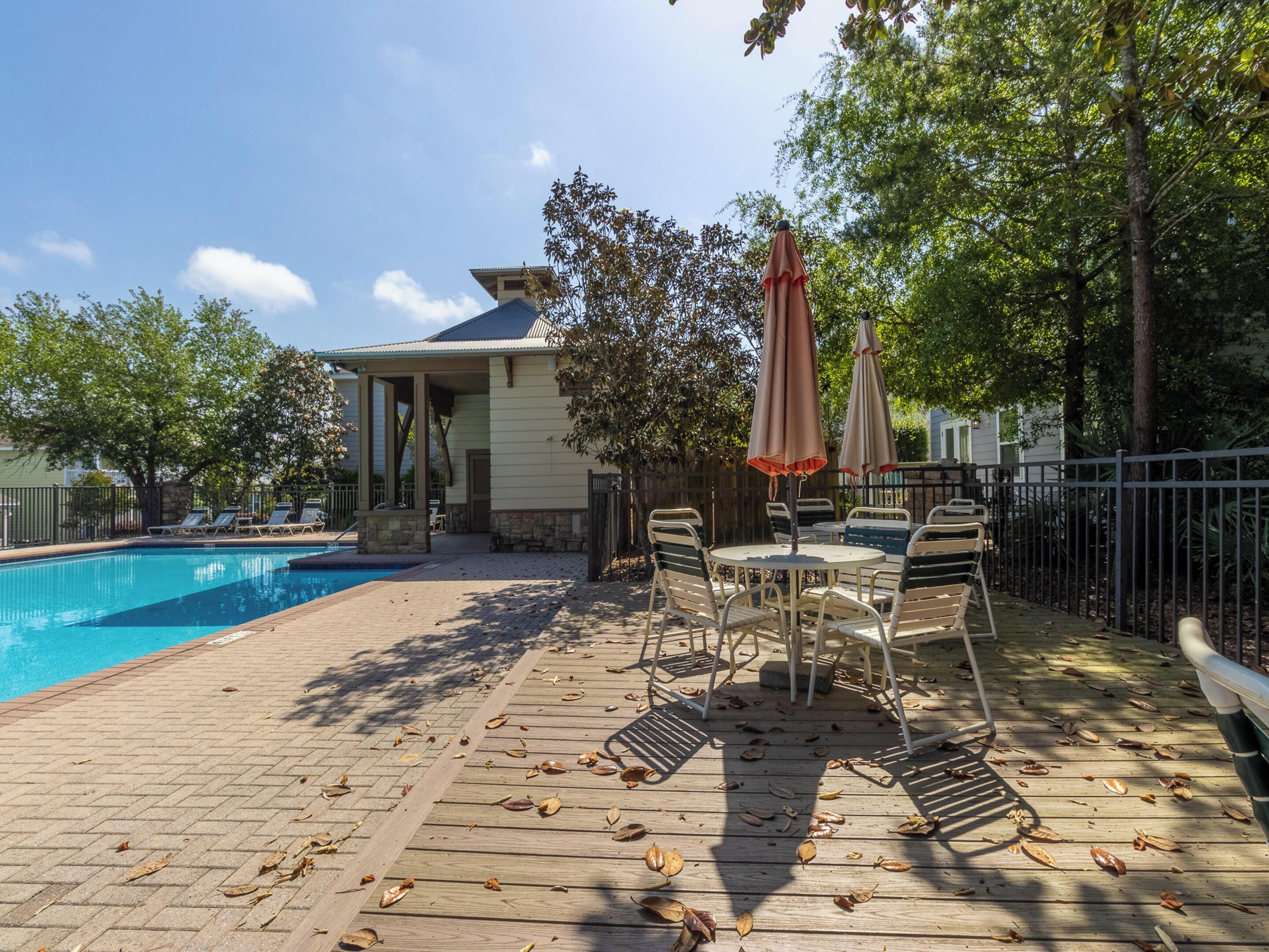 Un espace piscine doté d’une terrasse en bois, de chaises longues et de parasols.