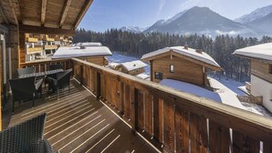 A wooden deck with a view of snow-covered houses and mountains. - Stylish Alpine Chalet With Carport (Neukirchen am Grossvenediger)