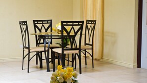Un comedor con una mesa redonda y sillas, un jarrón con flores y una cortina amarilla.